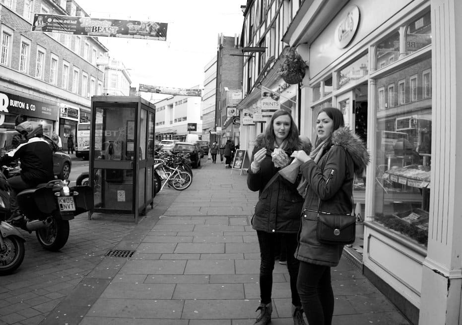 street photograph of 2 women eating outside cake shop